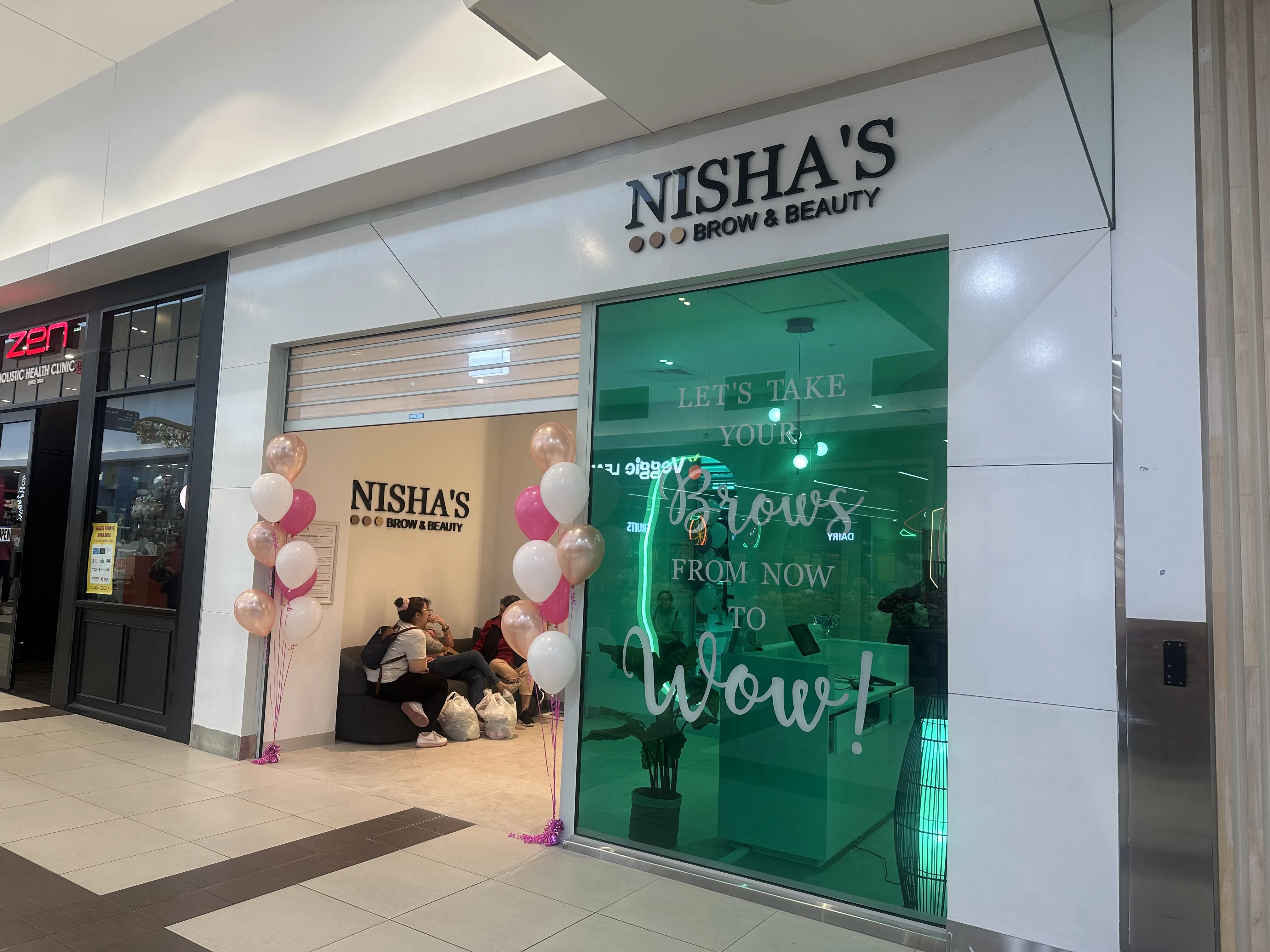 Nisha's Brow & Beauty storefront with 'now to wow' window decal