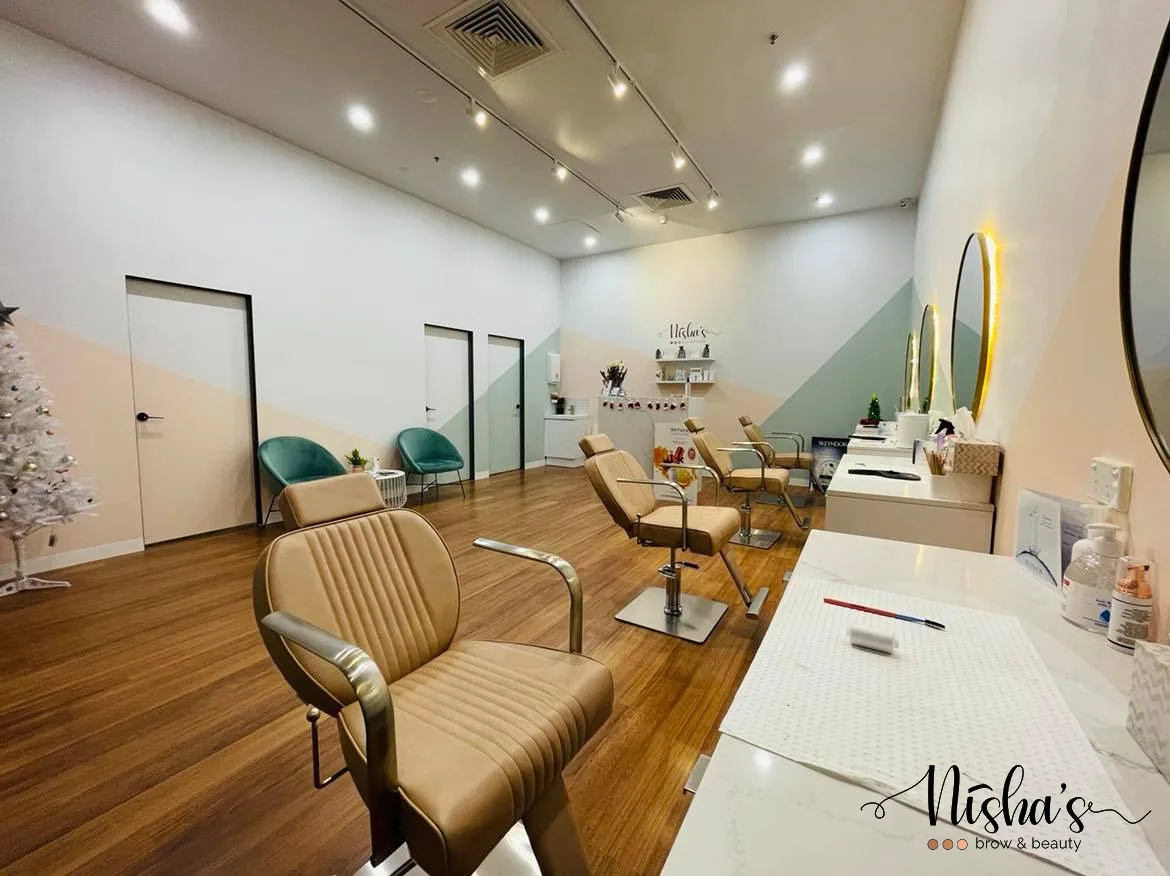Inside Nisha's Brow & Beauty — styling chairs and gold-framed mirrors
