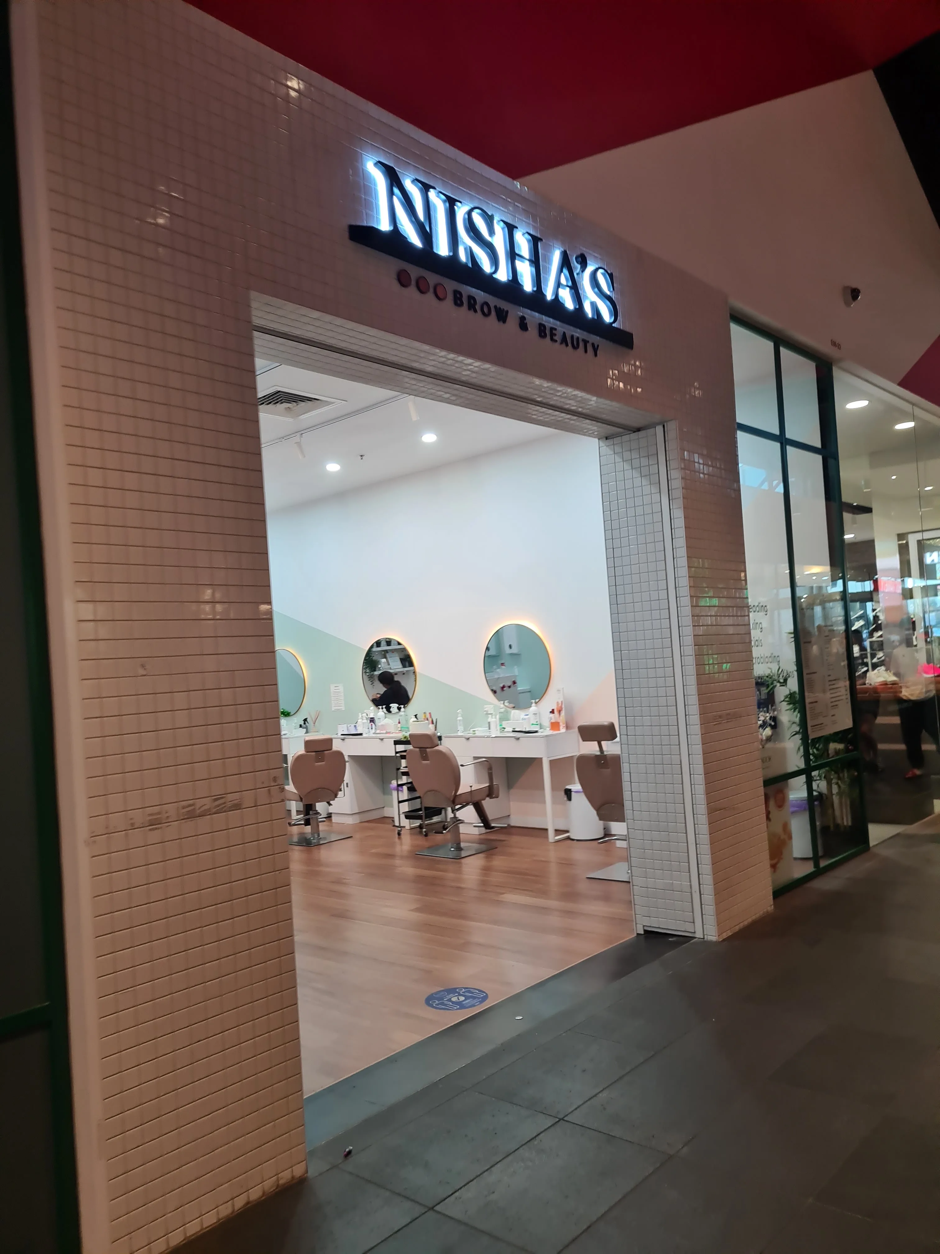 The illuminated Nisha's Brow & Beauty shopfront at night